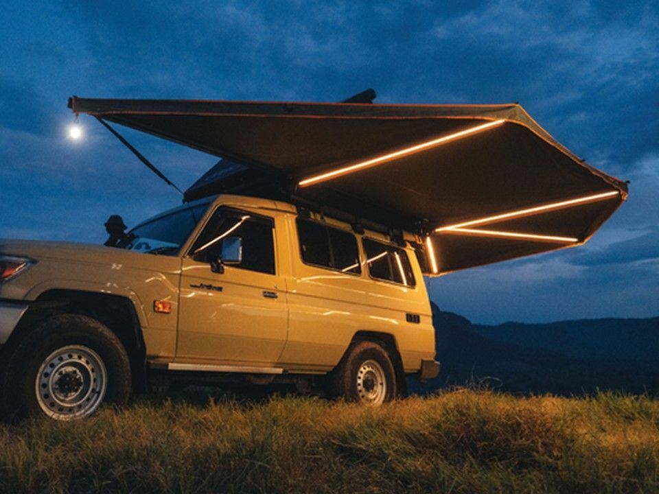 Geländewagen mit ausgefahrener Darche-270°-Markise und LED-Licht in der Abenddämmerung