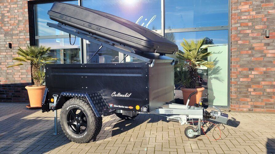 Schwarzer Offroad-Dachzeltanhänger mit Offroad-Bereifung und Alufelgen vor dem Showroom