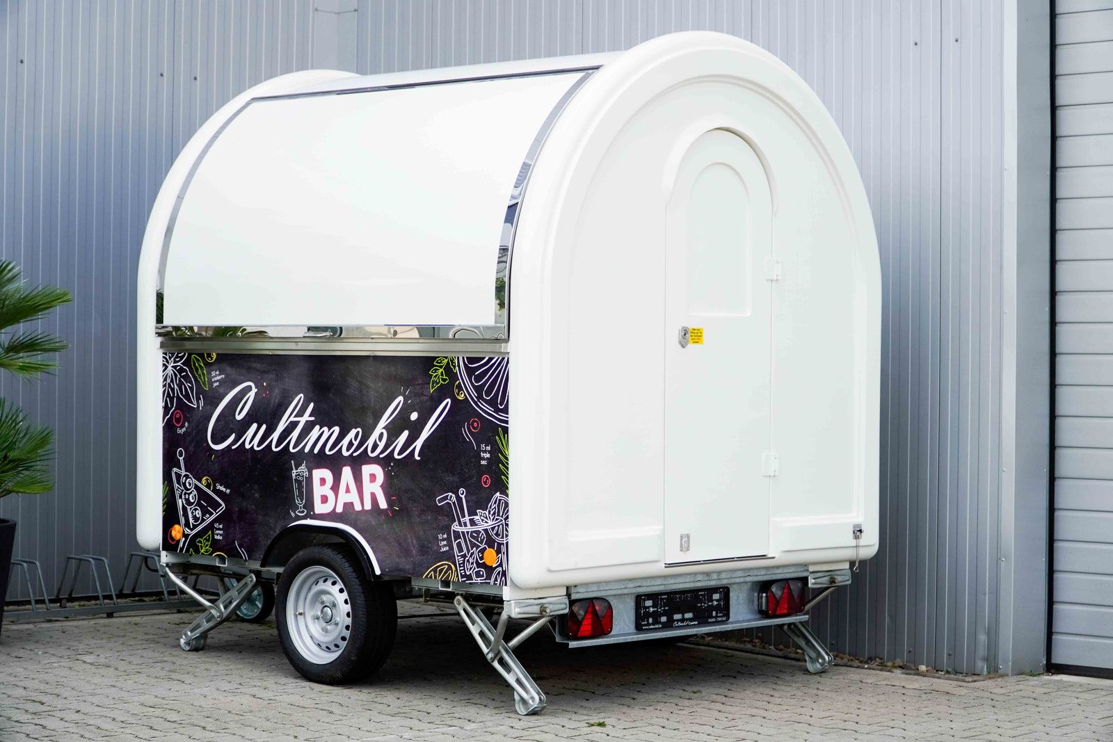 Ein weißer Foodtrailer mit zugeklappter Verkaufsklappe.
