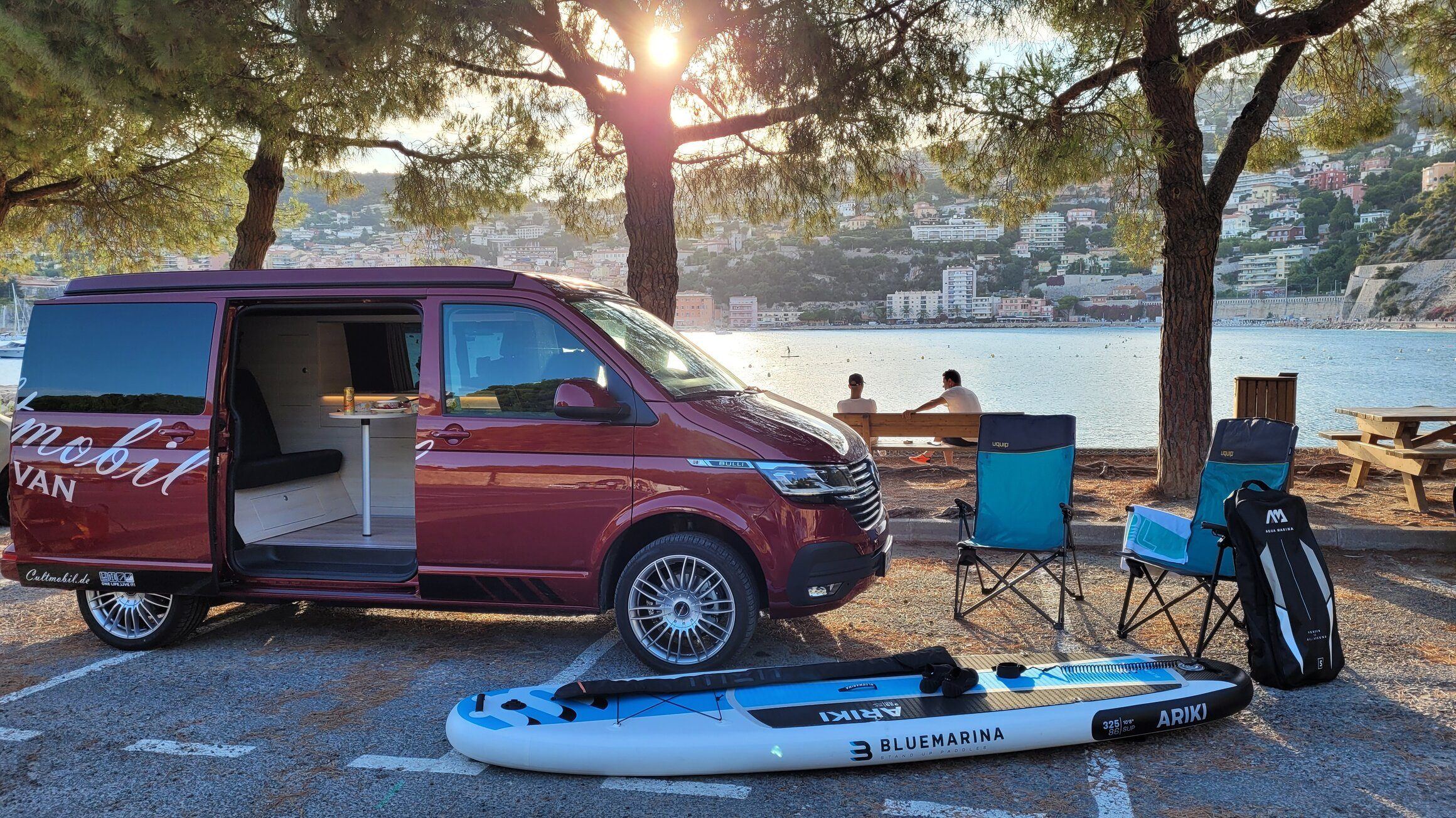 Roter Cultmobil VW Camper mit Aufstelldach am Hafen von Nizza in der Abenddämmerung
