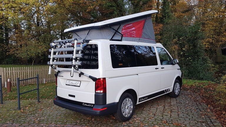 Weißer Bus mit aufgestelltem Dach und Fahrrädern
