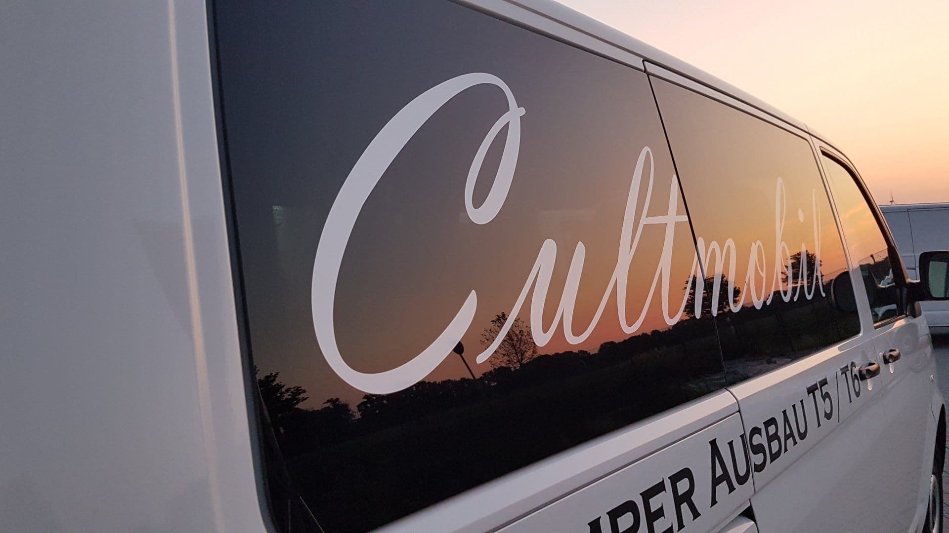 Cultmobil-Schriftzug auf einem Bus im Sonnenuntergang